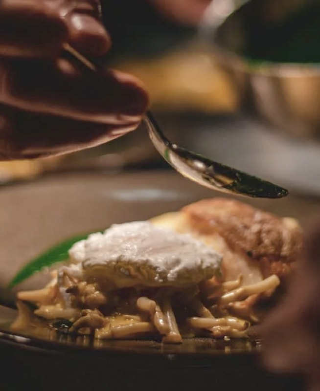 hand with spoon over a plate of food